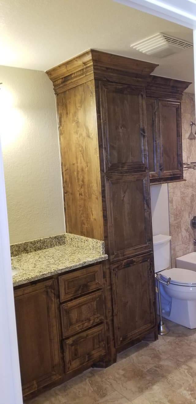 A bathroom with a sink , toilet and cabinets.