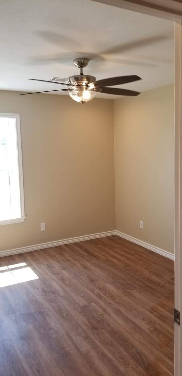 An empty living room with hardwood floors and a ceiling fan.