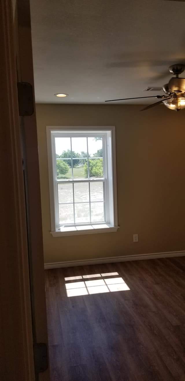 An empty room with a window and a ceiling fan.