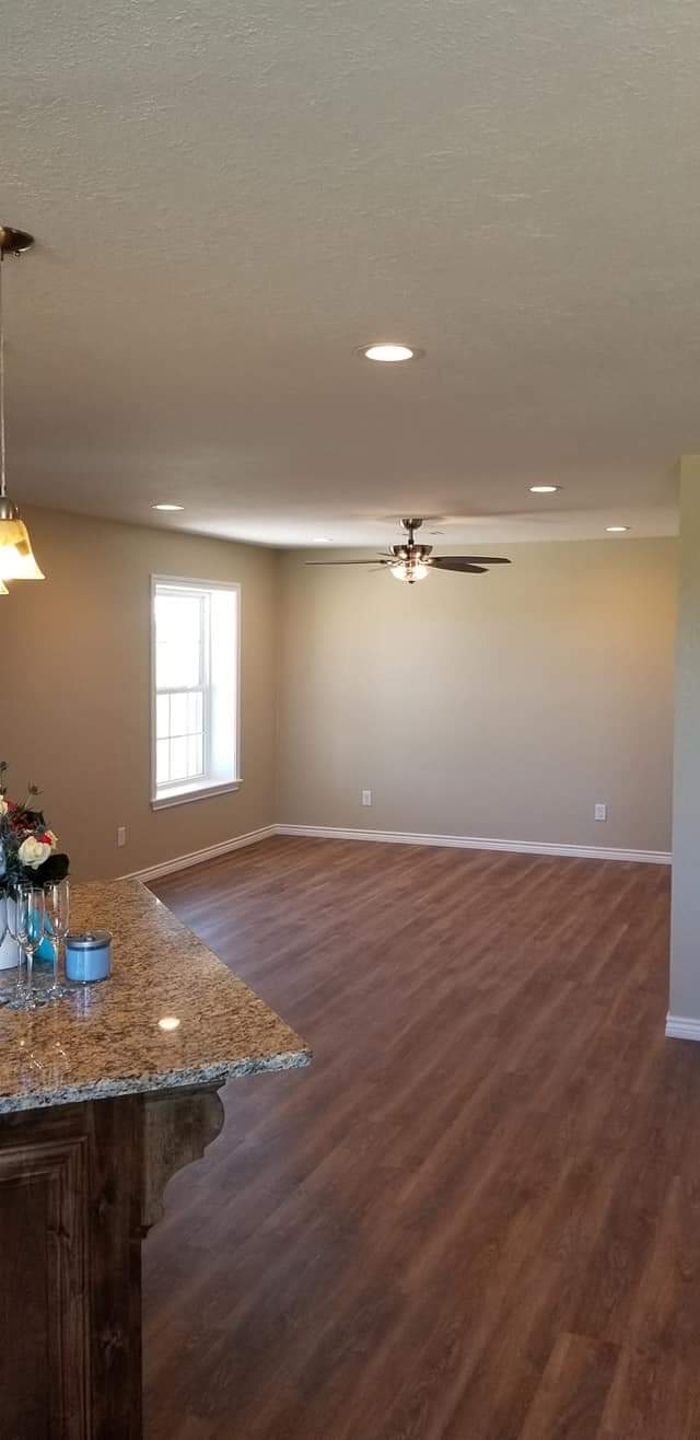 An empty living room with hardwood floors and a ceiling fan.