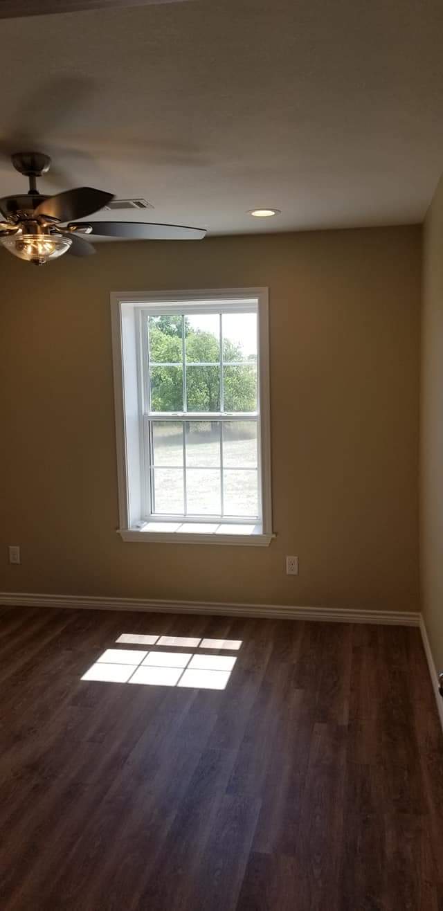 An empty room with a window and a ceiling fan.