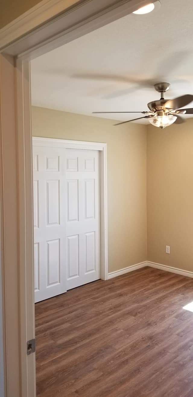 A bedroom with hardwood floors and a ceiling fan.