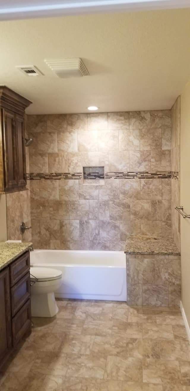 A bathroom with a tub , toilet , sink and shower.