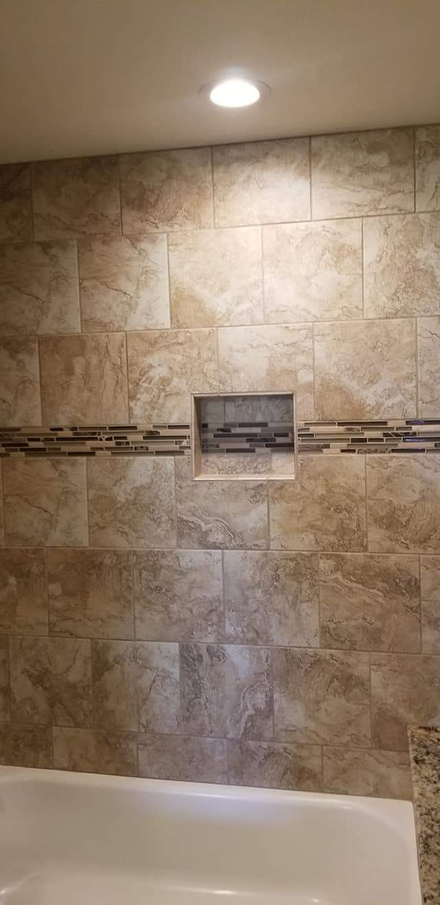 A bathroom with a bathtub and a tiled wall.