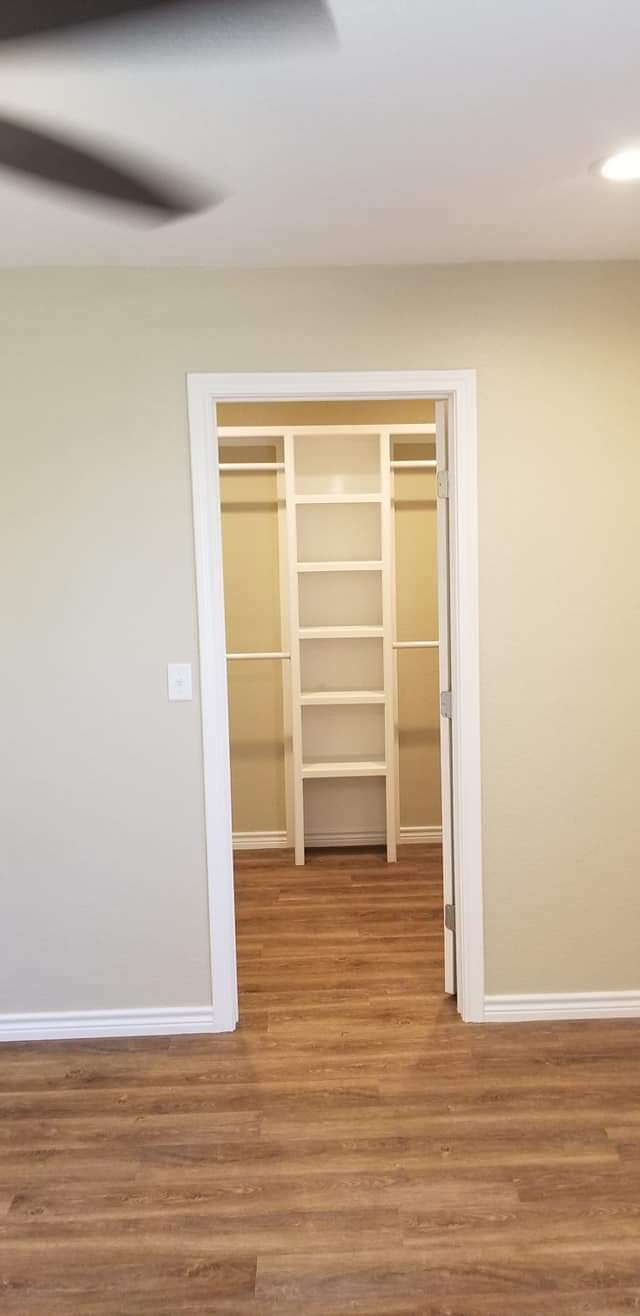 A walk in closet with a ladder and shelves in an empty room.