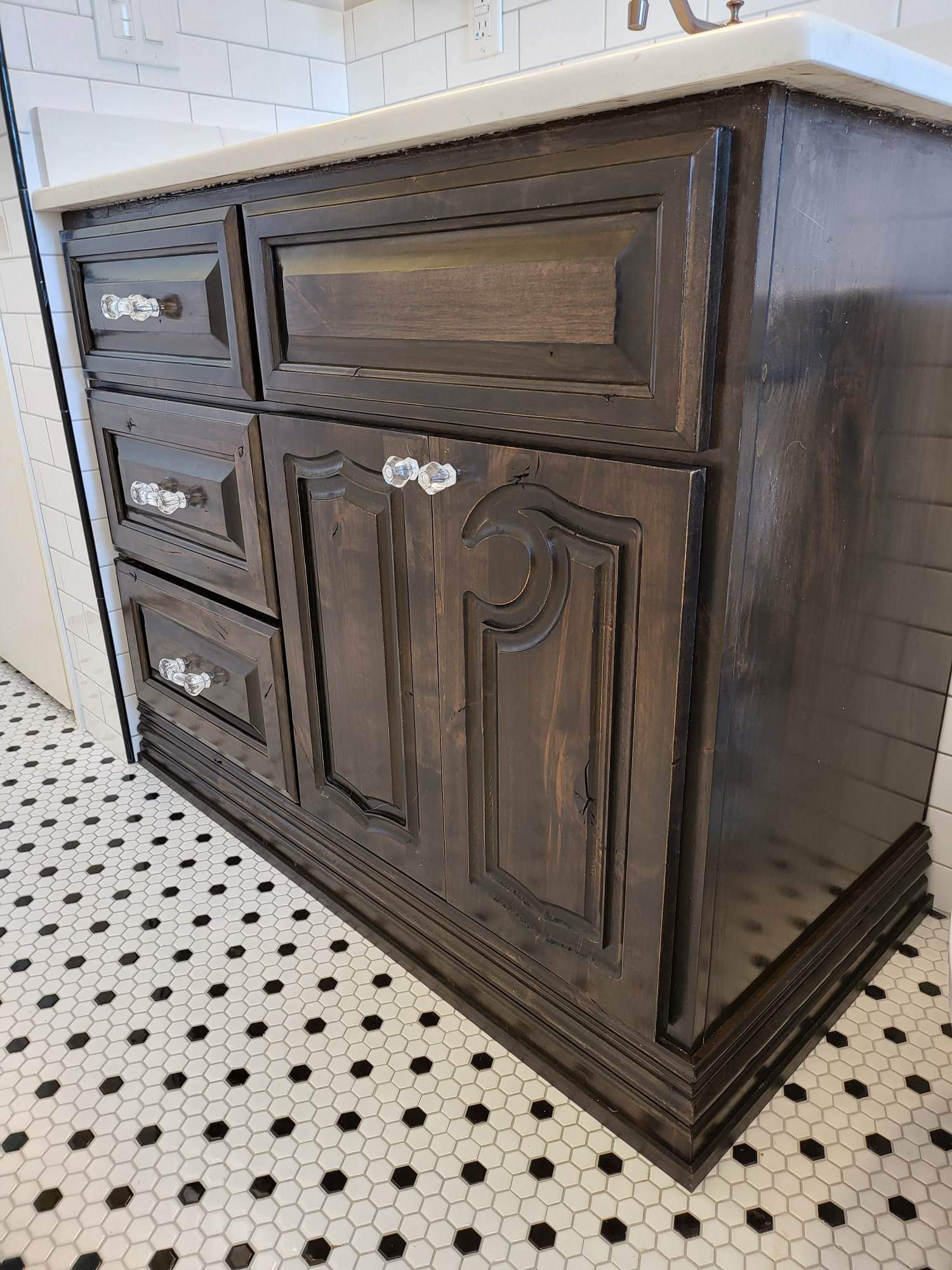 A bathroom vanity with drawers and cabinets next to a sink.