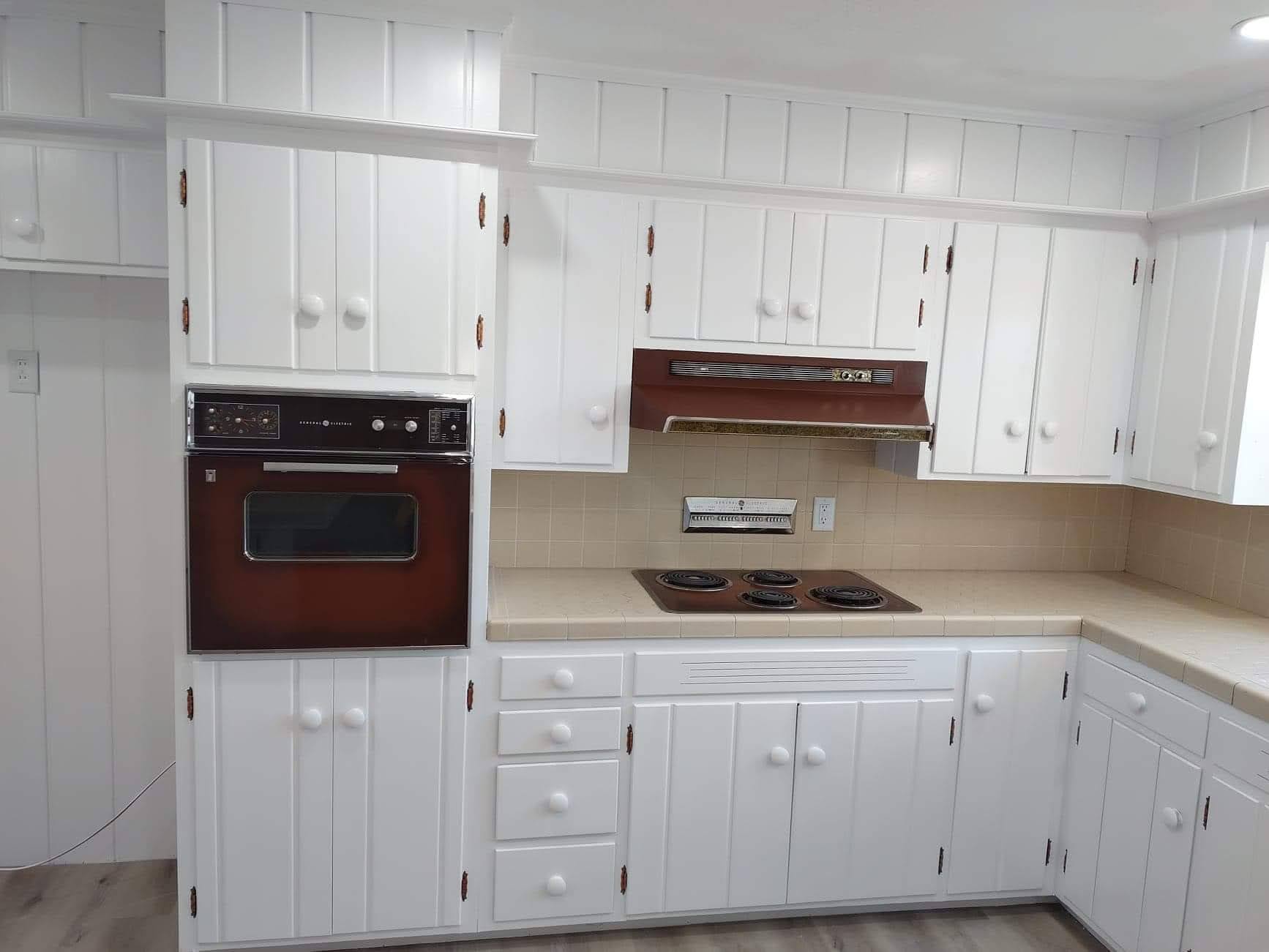 A kitchen with white cabinets and a brown oven