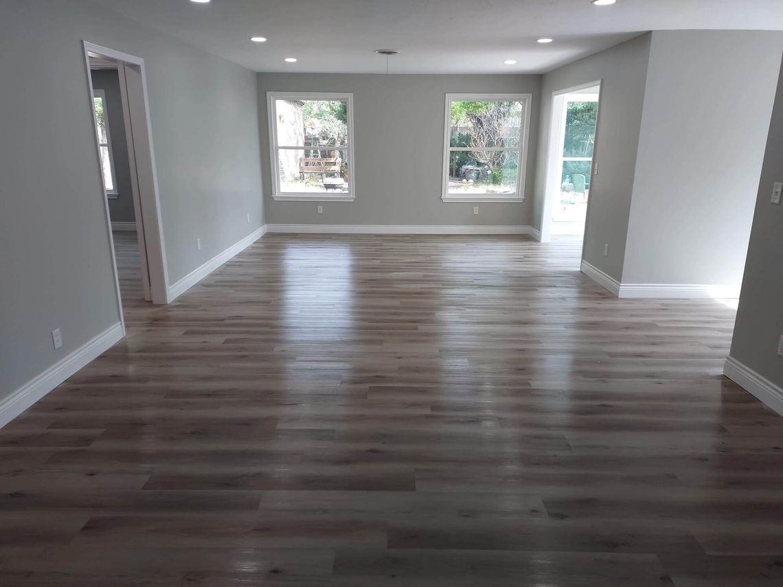 An empty living room with hardwood floors and gray walls.