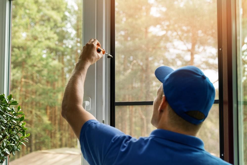 A Man Is Fixing a Window with A Screwdriver — ACG Windows & Glass in Narre Warren, VIC