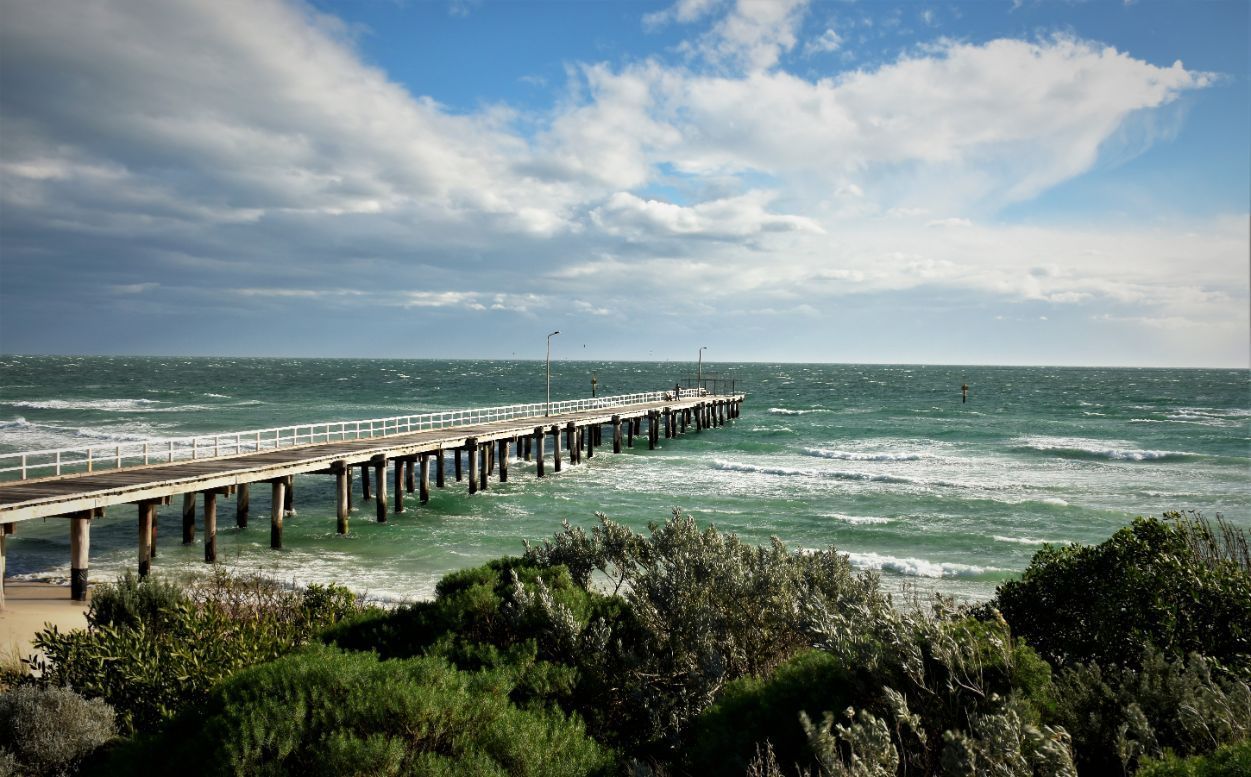 A Pier Leading Into the Ocean on A Cloudy Day — ACG Windows & Glass in Seaford, VIC