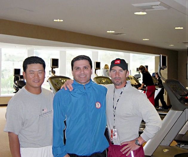 Three men are posing for a picture in a gym