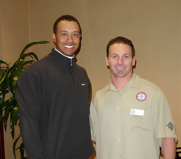 Two men are posing for a picture and one has a name tag on his shirt