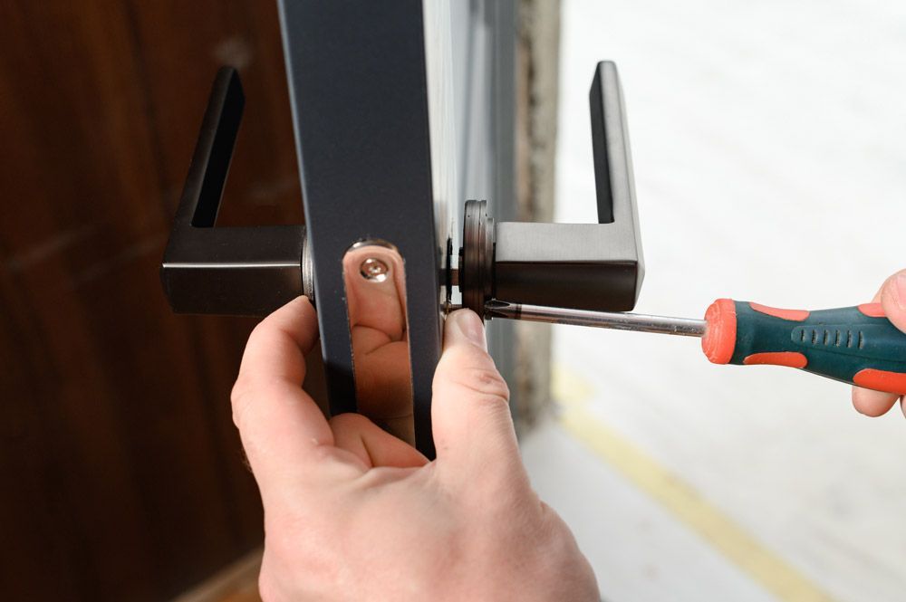 A person is fixing a door handle with a screwdriver.
