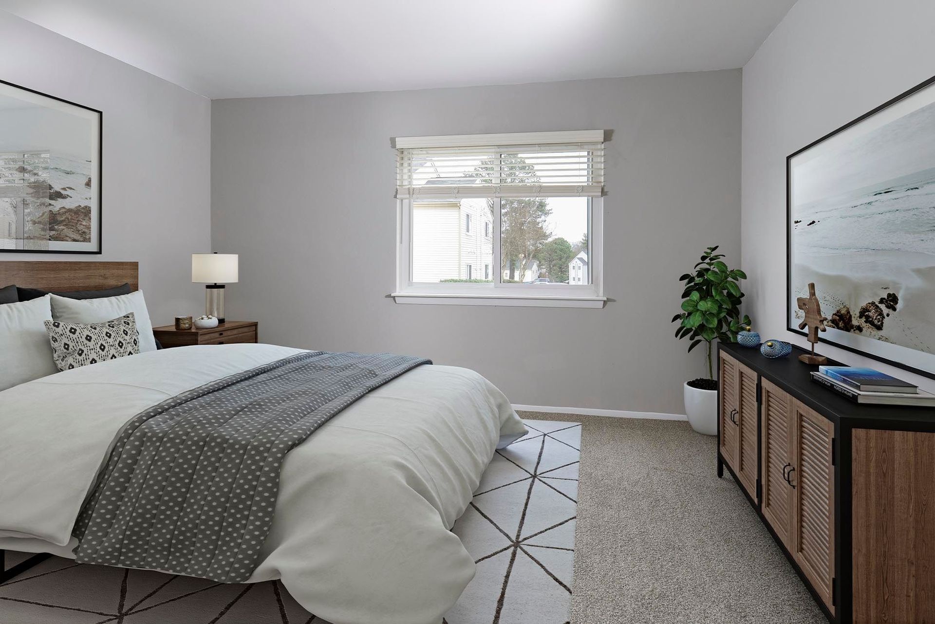 Bedroom with bed, nightstand, dresser, and window. Neutral color scheme; rug on carpet.