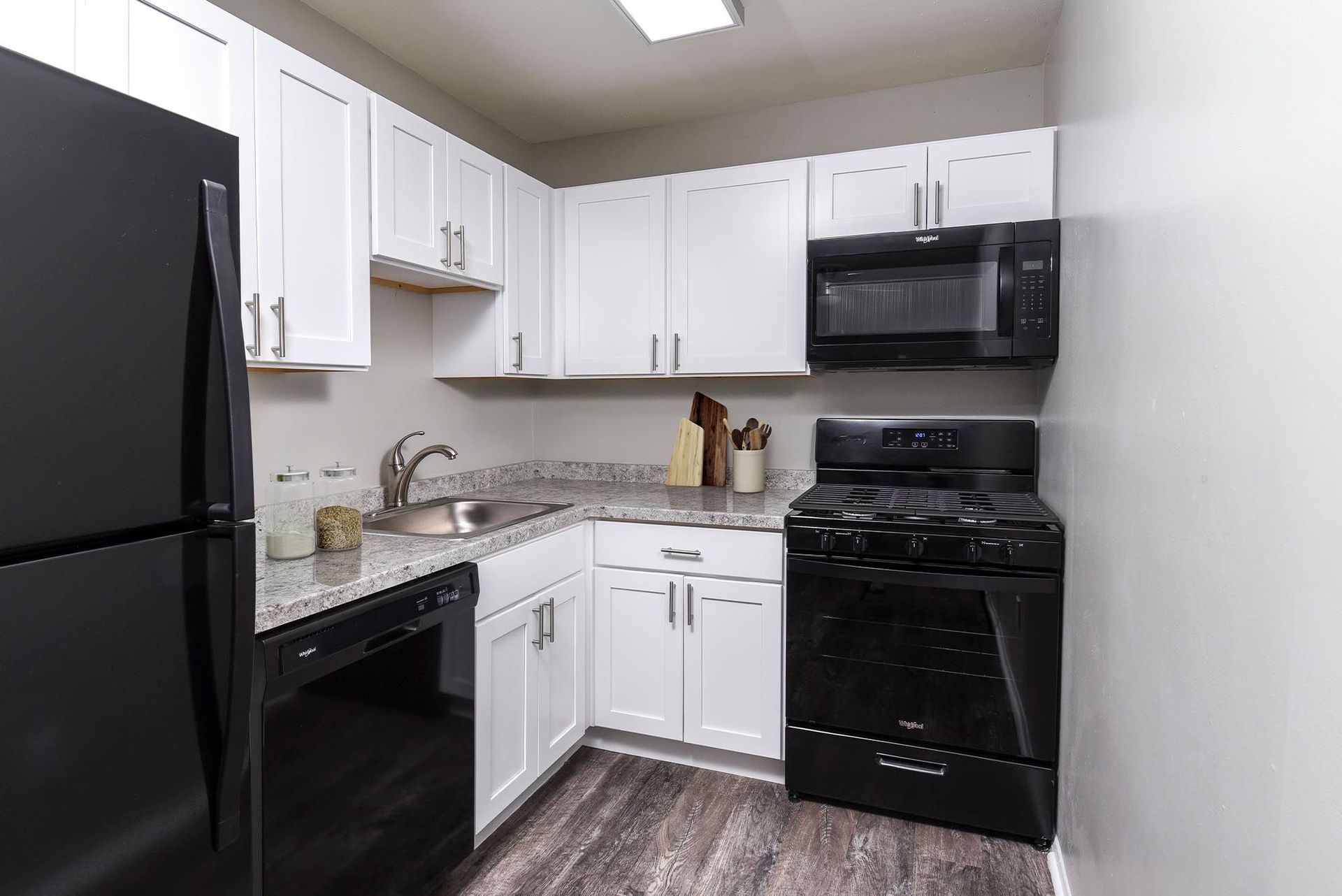 A small kitchen with white cabinets, black appliances, and gray countertops.