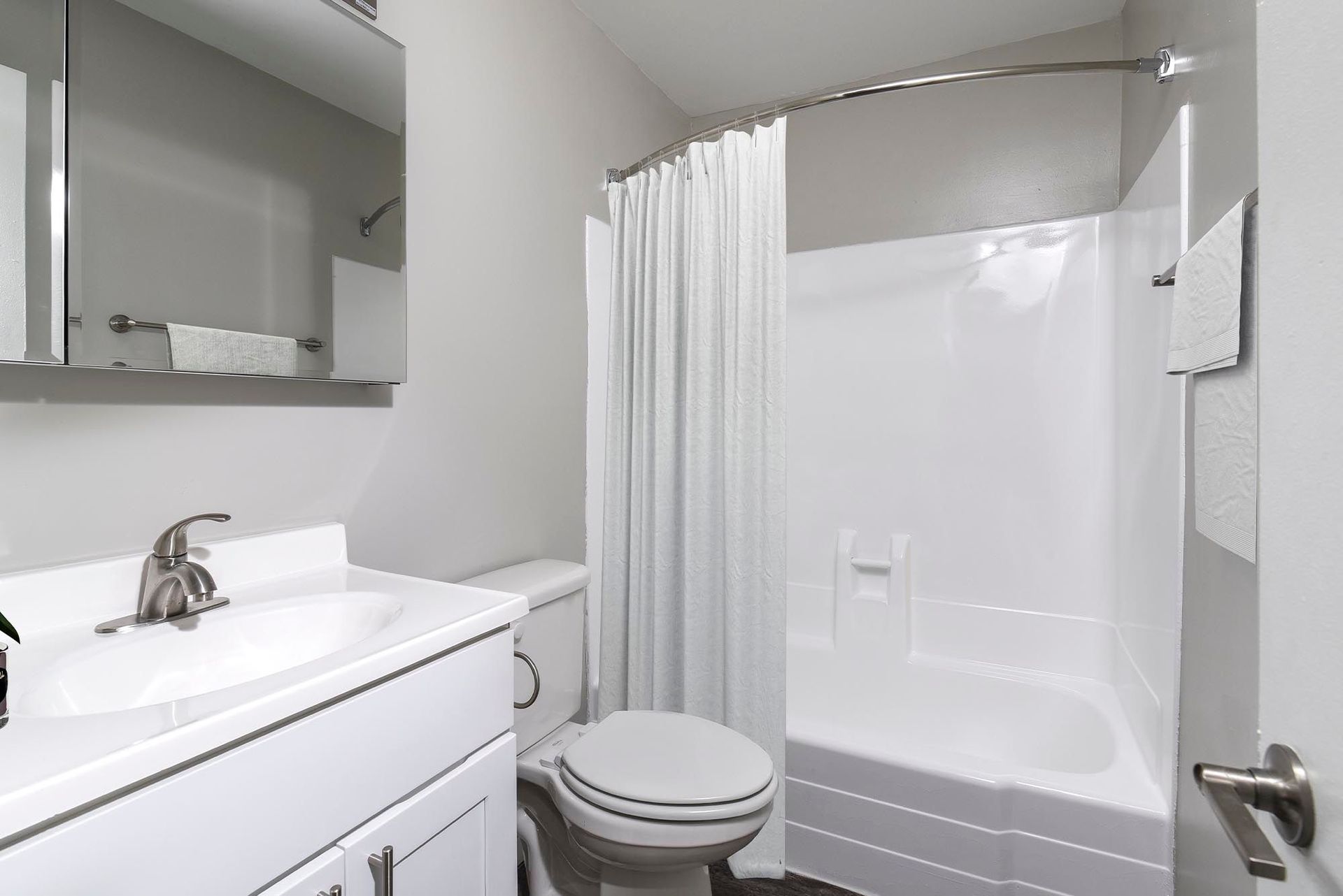 A small, white bathroom with a sink, toilet, and shower/tub combo.