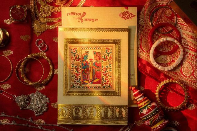 Red and gold festive gift box with ornate jewelry and decorative bangles on a red fabric background