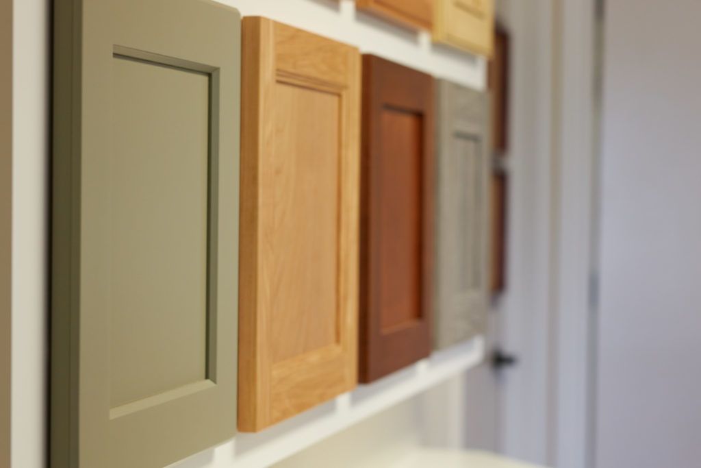 a row of cabinet doors of different colors are lined up on a wall .
