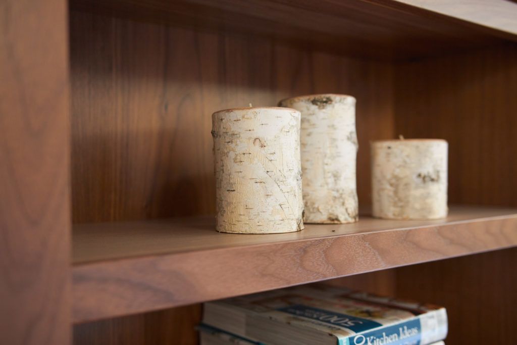 three candles are sitting on a wooden shelf next to a stack of books .