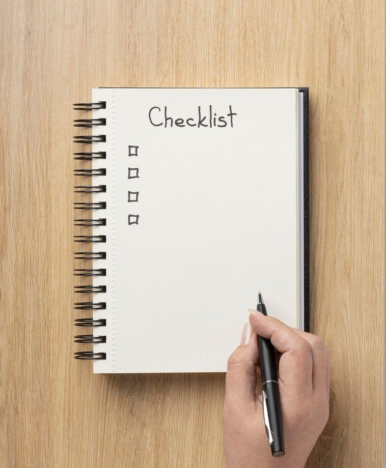 a person is writing a checklist in a notebook with a pen .