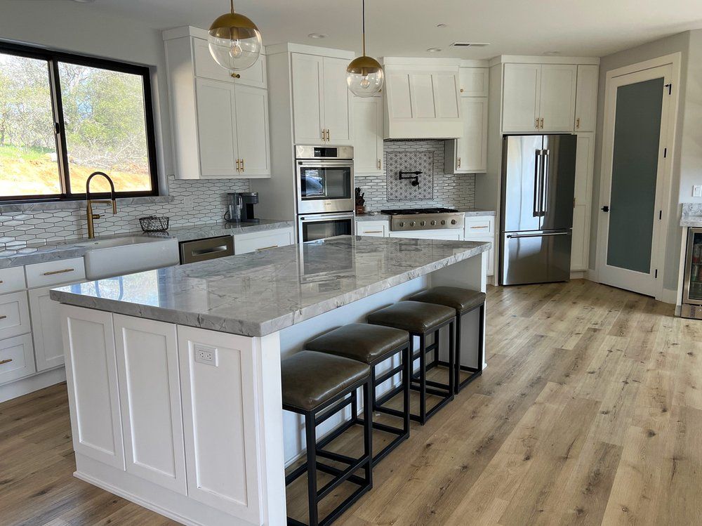 a kitchen with white cabinets , granite counter tops , stainless steel appliances and a large island .