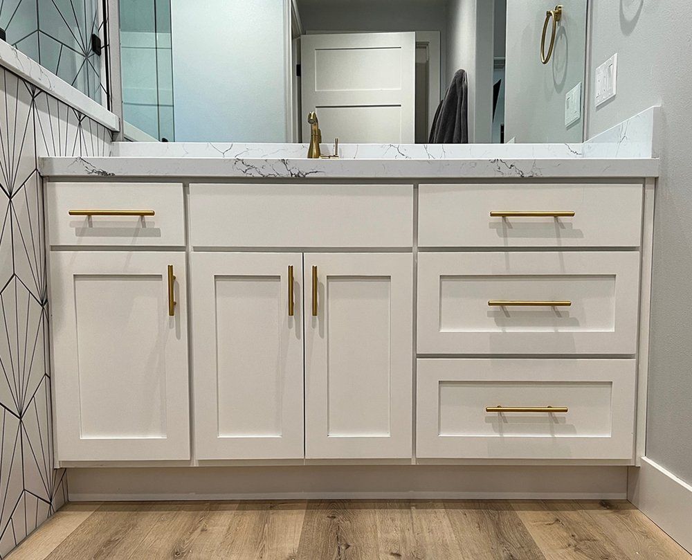 a bathroom with white cabinets , drawers , a sink and a mirror .