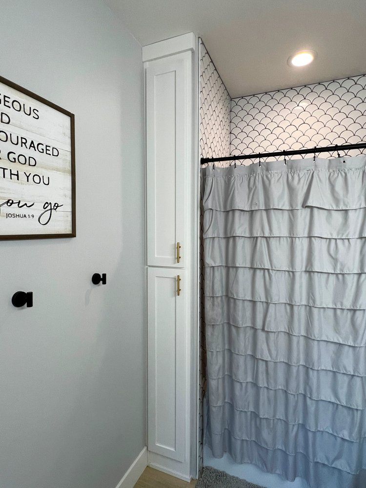 a bathroom with a shower curtain and a sign on the wall .