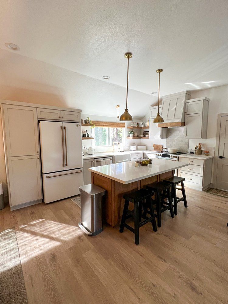 a kitchen with a large island , stools , and a refrigerator .