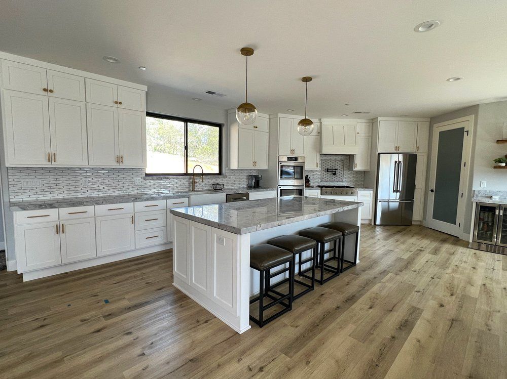 a kitchen with white cabinets , granite counter tops , stainless steel appliances and a large island .