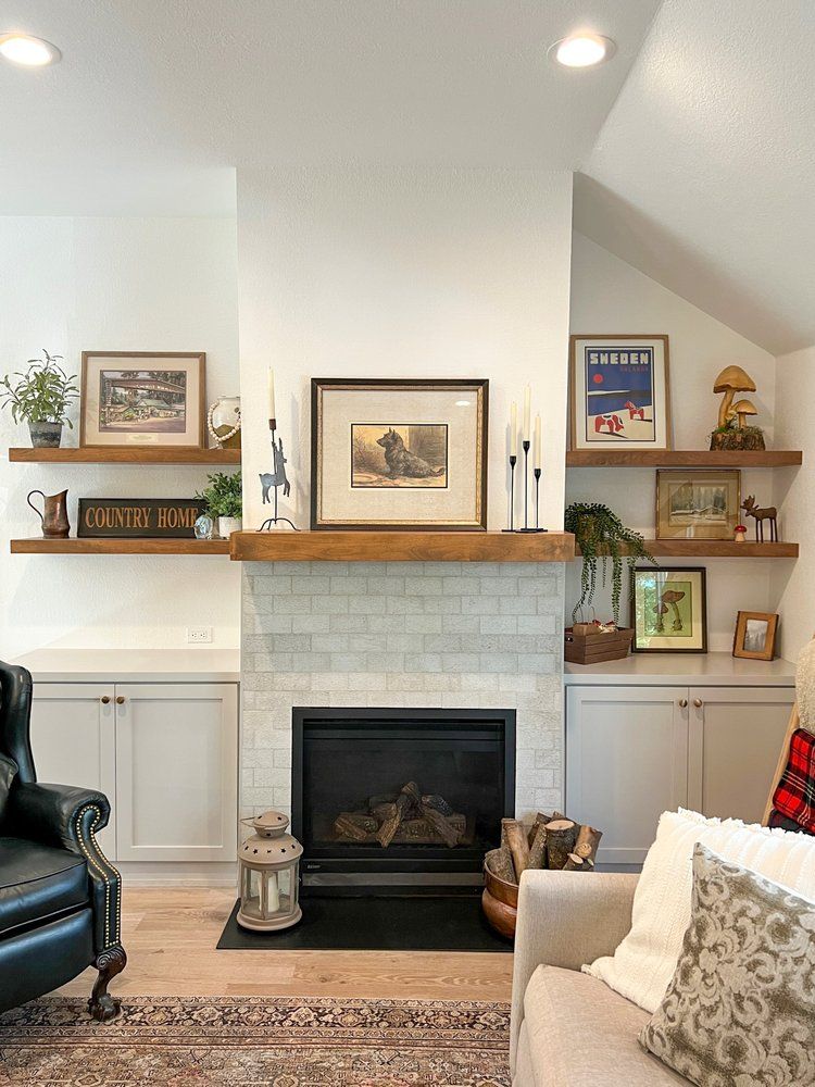 a living room with a fireplace , couch , chair and shelves .