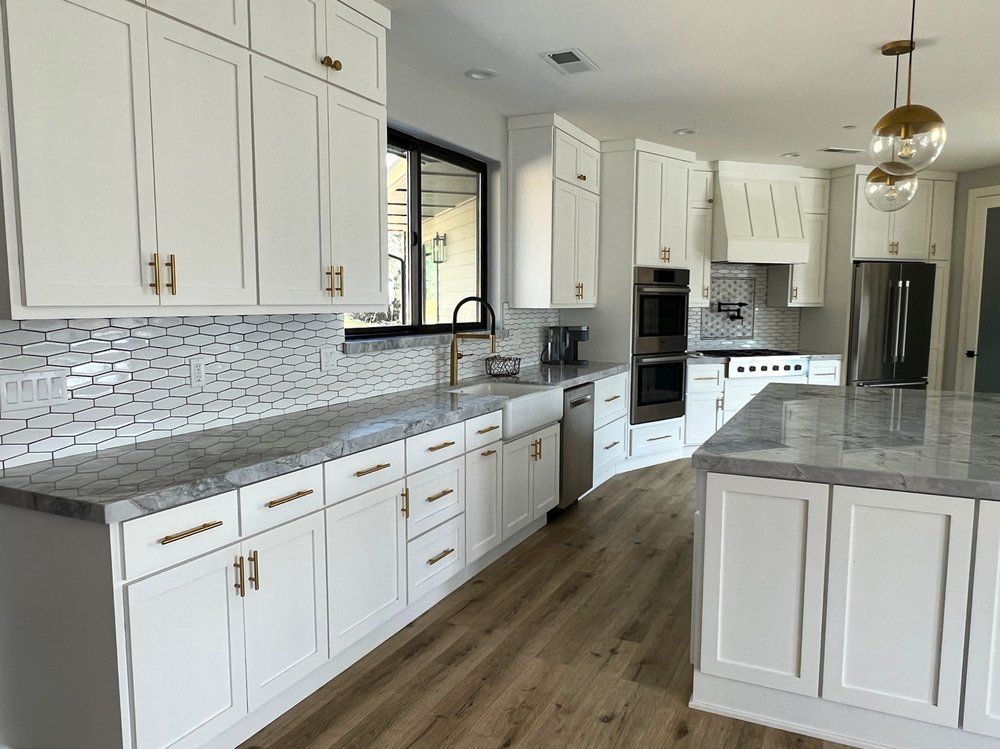 a kitchen with white cabinets , granite counter tops , and stainless steel appliances .