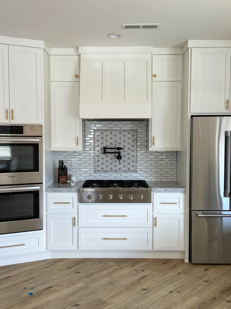 a kitchen with white cabinets , stainless steel appliances , a stove and a refrigerator .