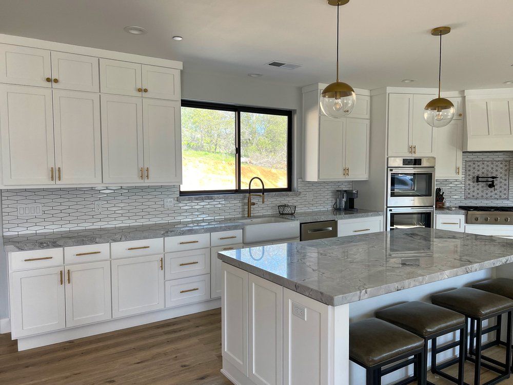 a kitchen with white cabinets , granite counter tops , stainless steel appliances and a large island .