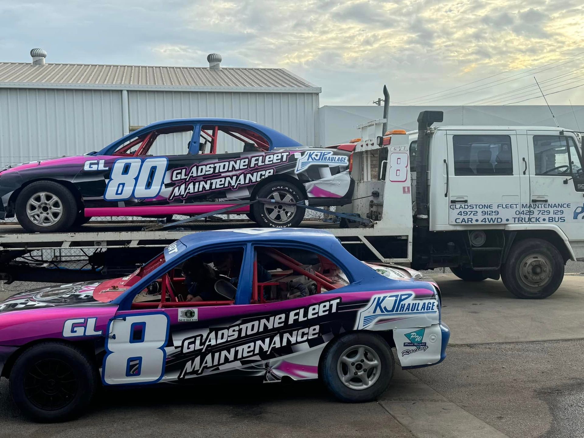 A gray pickup truck on a lift in a workshop, hood open. Another truck in the background, tools and equipment visible. — Gladstone Fleet Maintenance In Gladstone, QLD