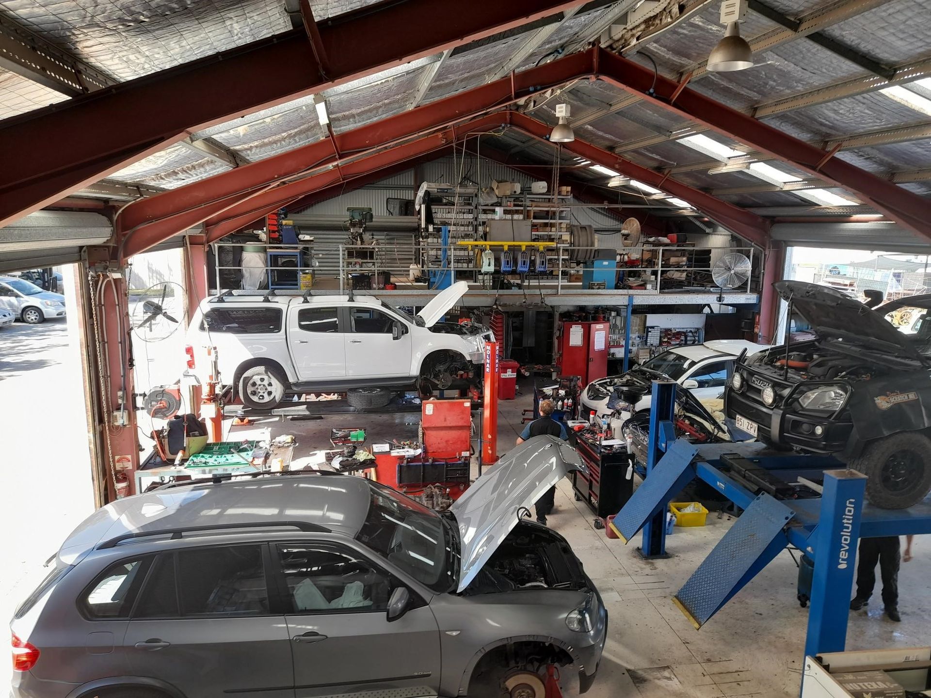 Cars in a garage being worked on, with open hoods. Tools and equipment scattered. — Gladstone Fleet Maintenance In Gladstone, QLD