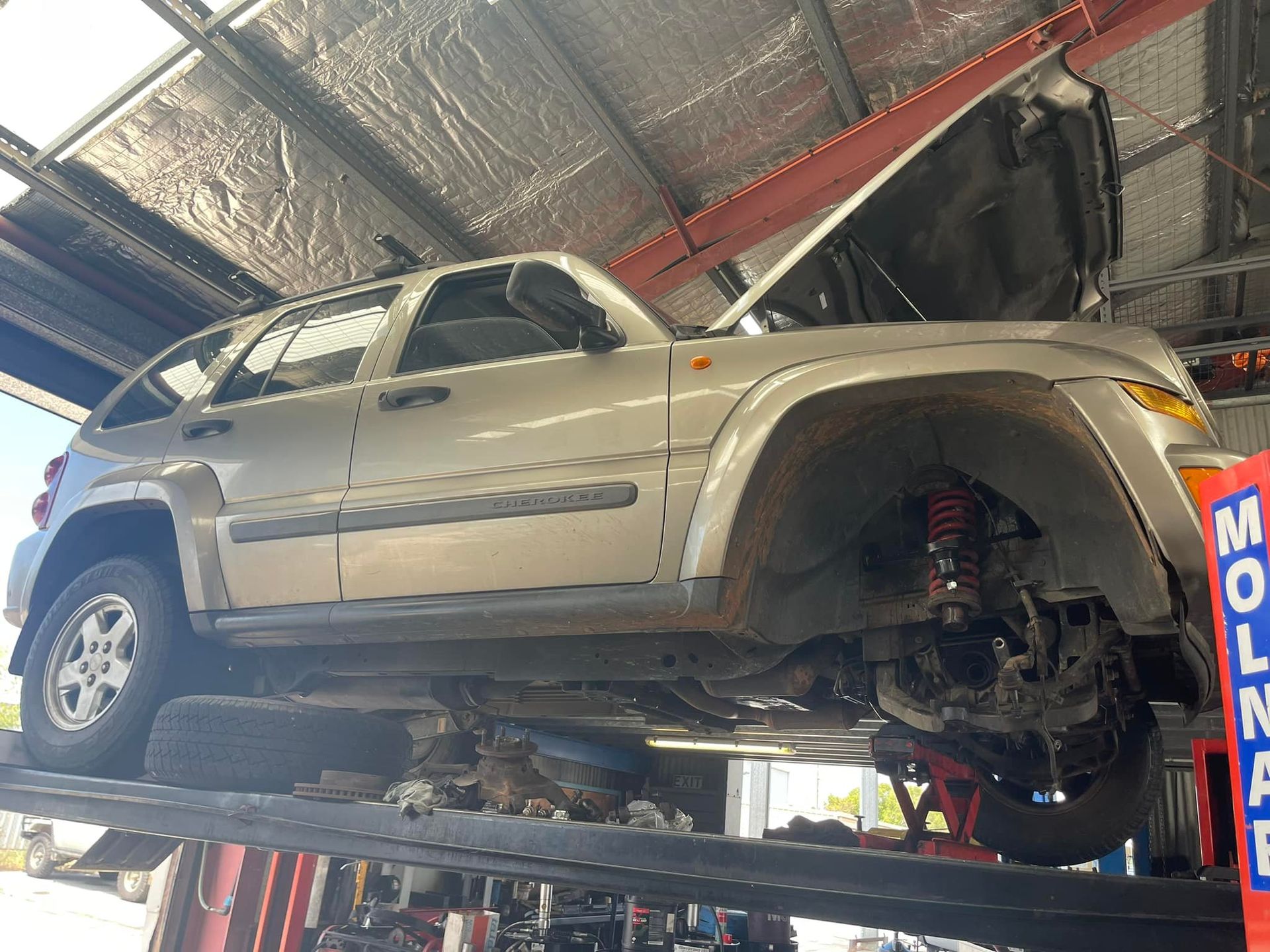 Silver Jeep Liberty on a Lift in a Mechanic — Gladstone Fleet Maintenance In Gladstone, QLD