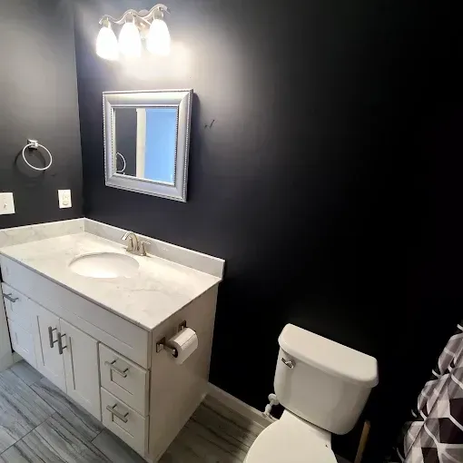 Bathroom with a white vanity, black walls, and a toilet.