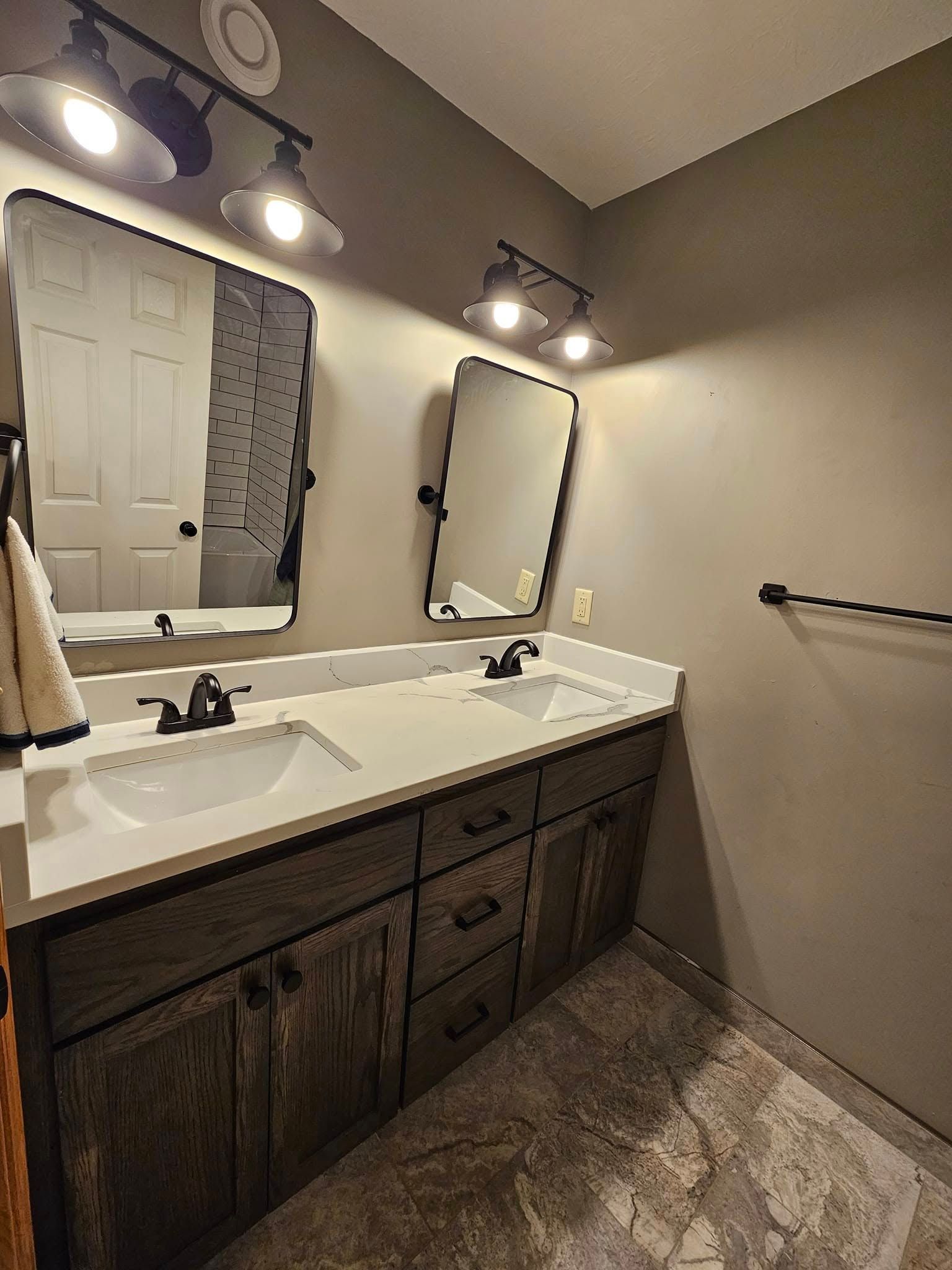 Bathroom with gray walls, wood cabinets, white countertop, dual sinks, and black-framed mirrors.