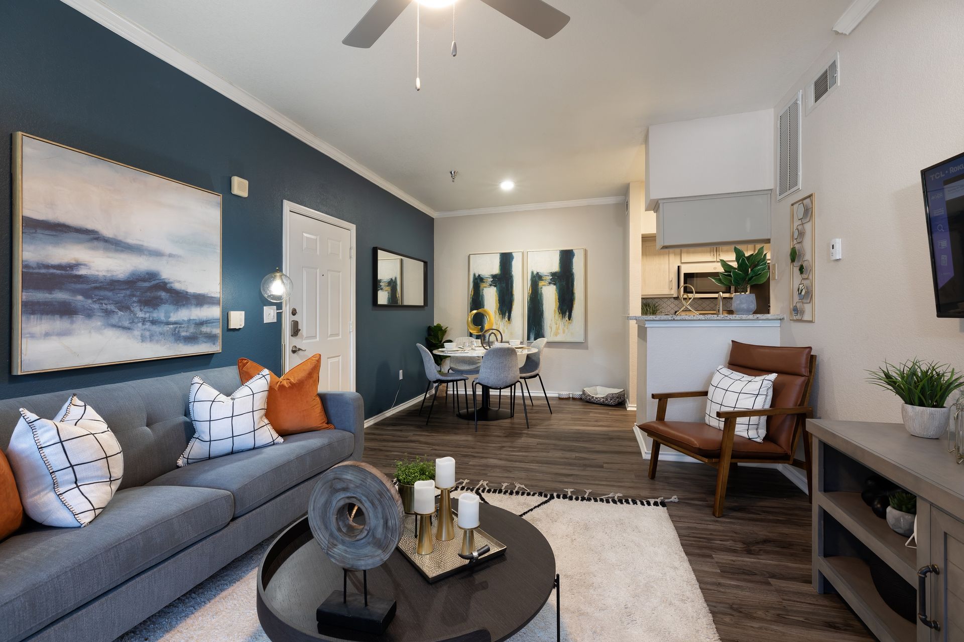 Living room with blue wall, gray sofa, art, and dining area.
