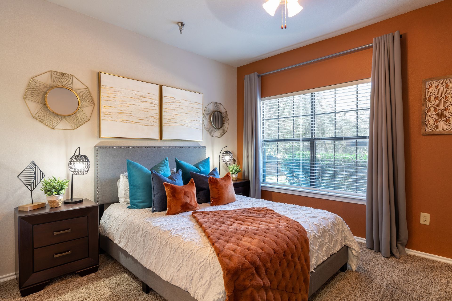 Bedroom with bed, nightstands, orange accent wall, window, and decorative pillows.