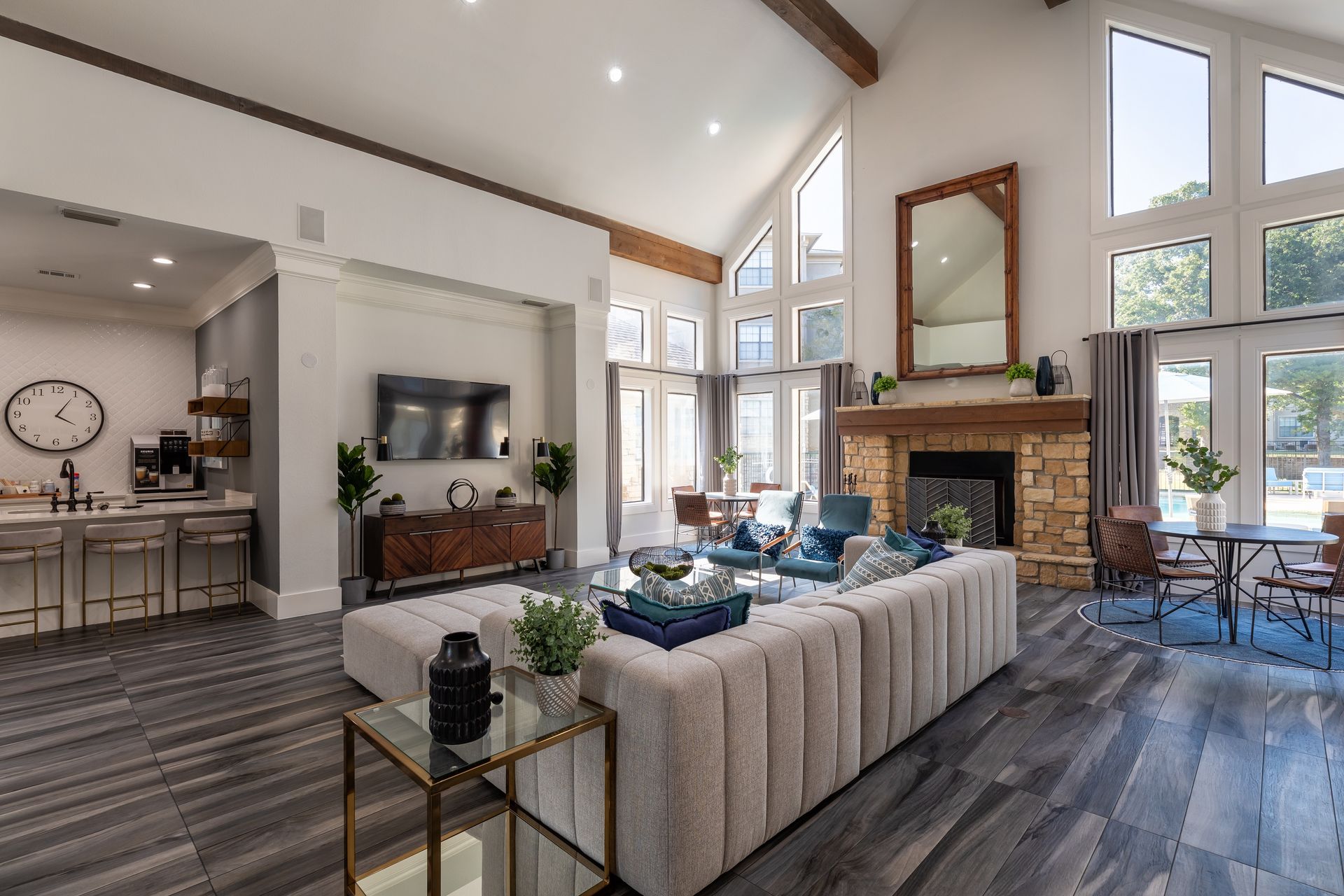 A large, bright living room with a fireplace, sofa, and large windows overlooking a pool area.