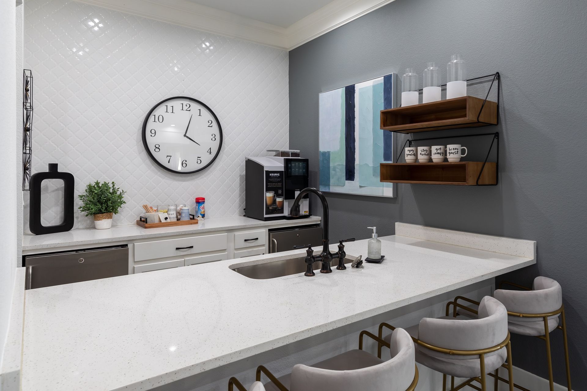 A modern office kitchenette with a white countertop, espresso machine, and seating.