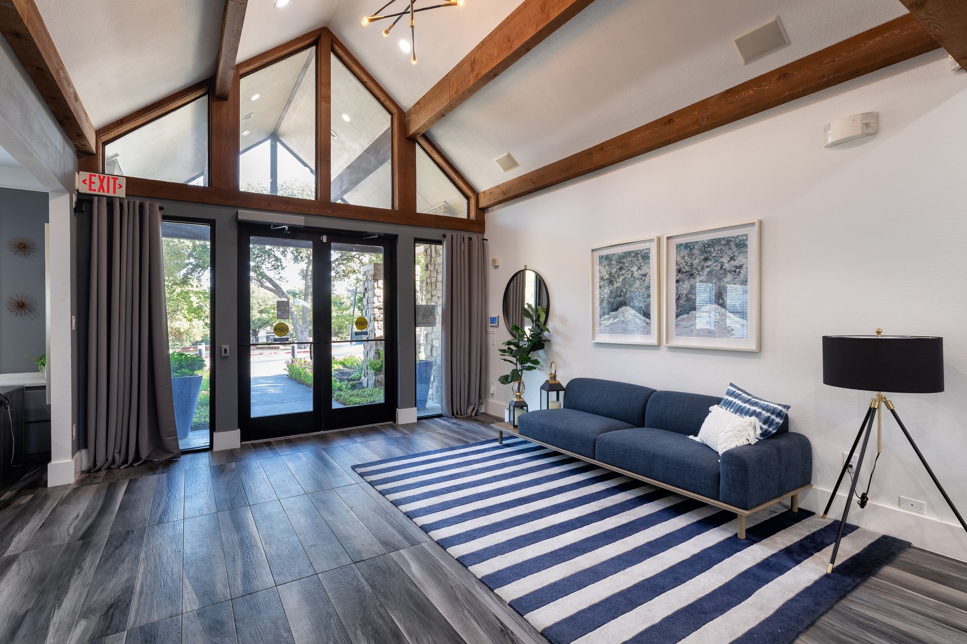 Lobby with blue and white striped rug, blue sofa, and large windows.