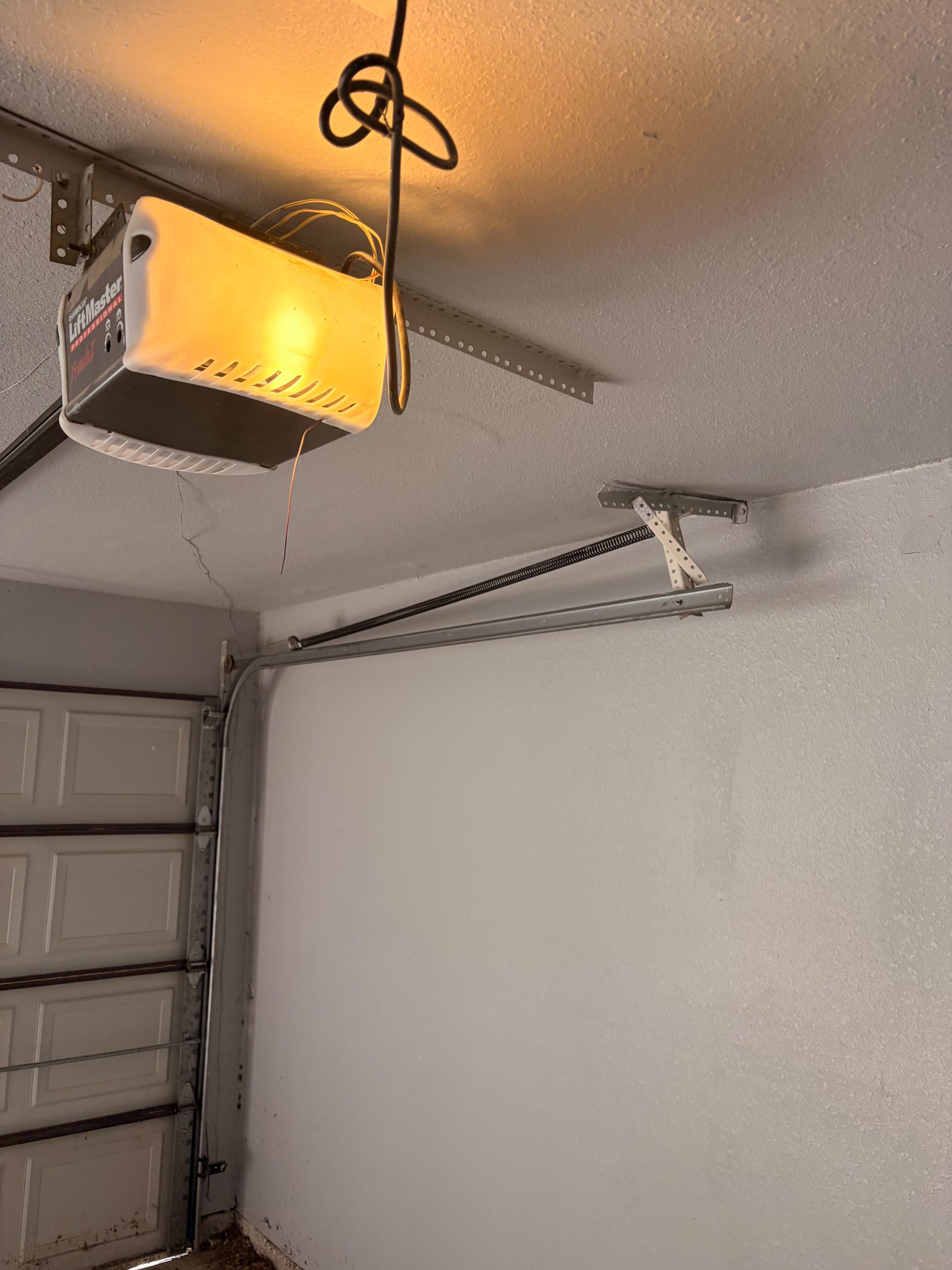 Garage ceiling with an open garage door opener and lit hanging light.