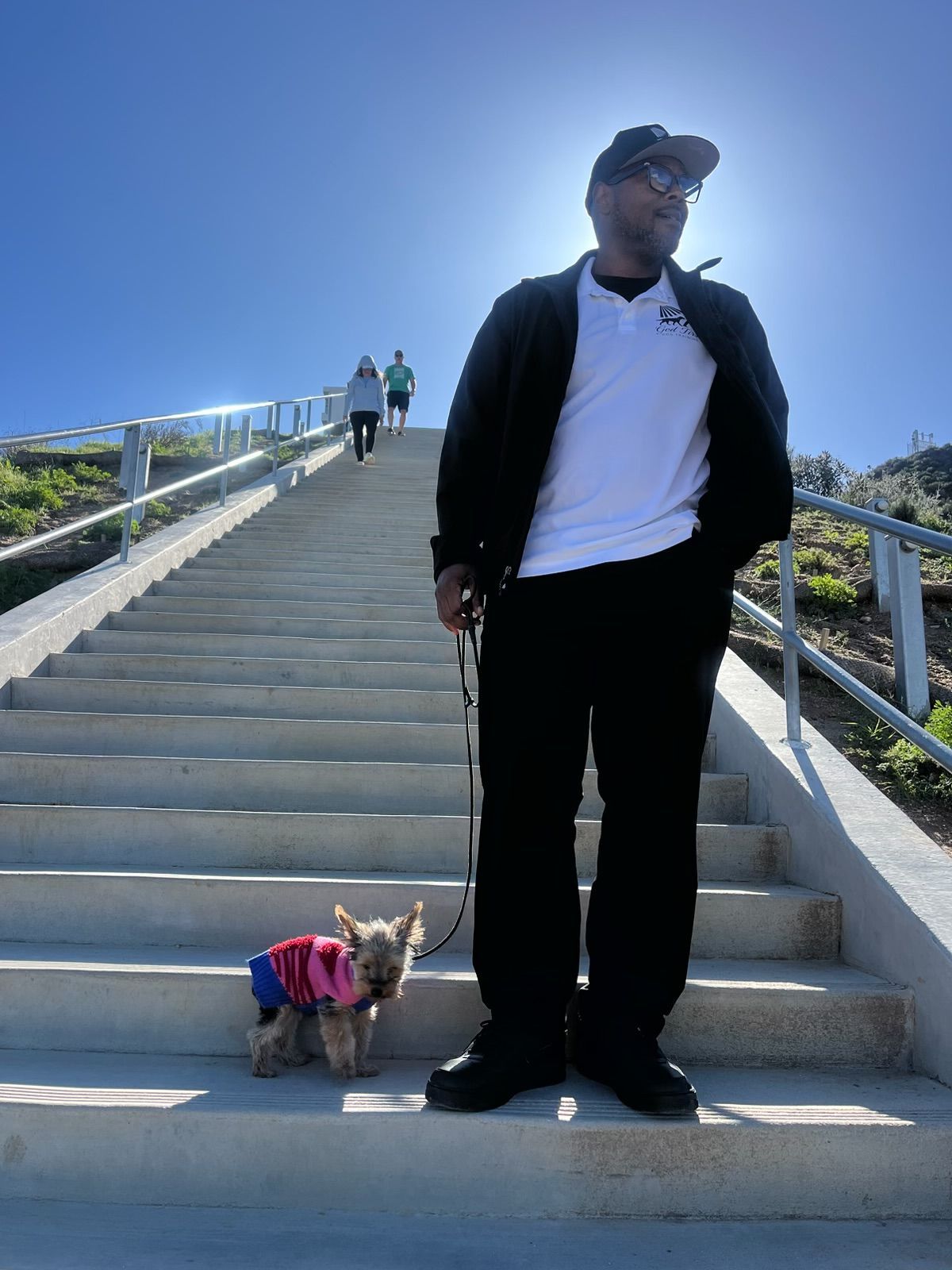 Woman in denim jacket hugging a black, brown, and white dog; smiling outdoors.