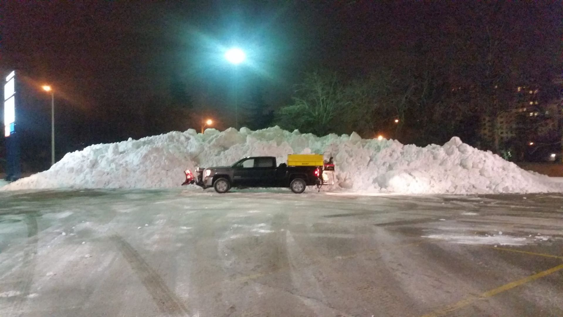 A truck is parked in front of a large pile of snow.