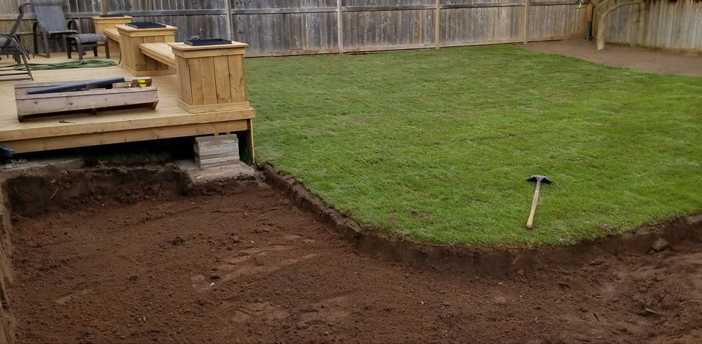 Backyard with newly dug soil, wooden deck, and a well-maintained lawn.