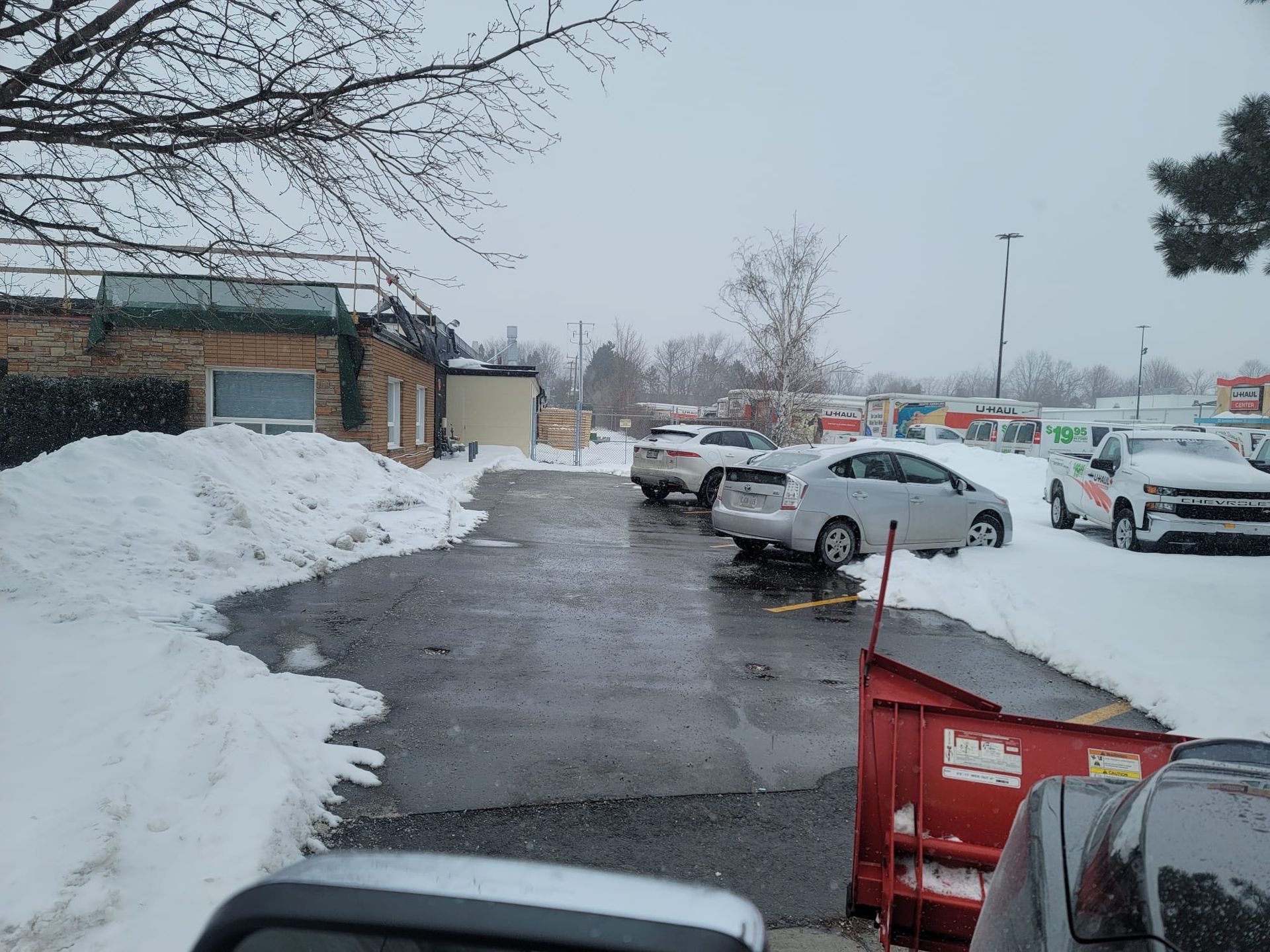 A parking lot covered in snow with cars parked in front of a building.