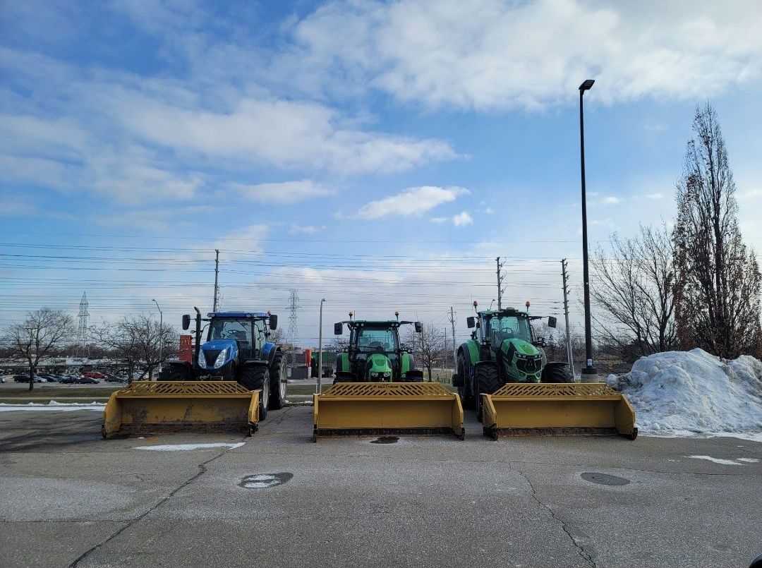 Three tractors are parked next to each other in a parking lot.