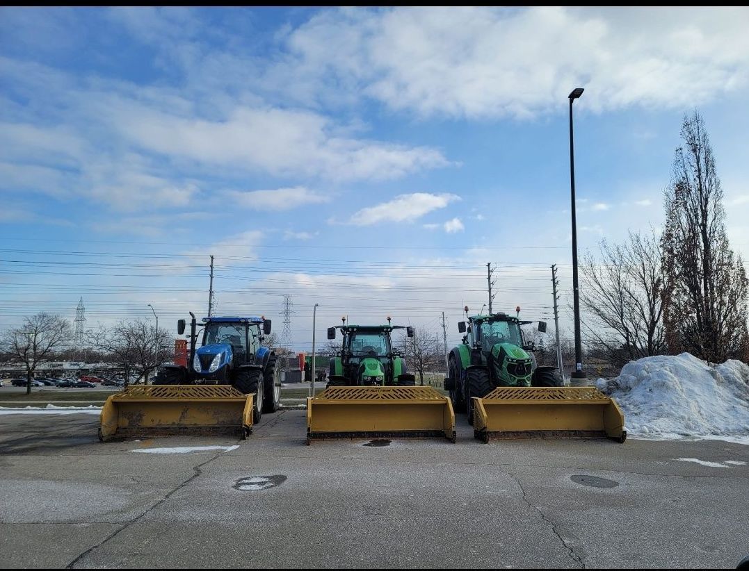 Three tractors are parked next to each other in a parking lot.